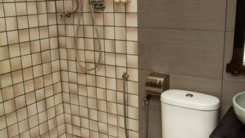 A bathroom with a toilet, a shower, and a towel rack.