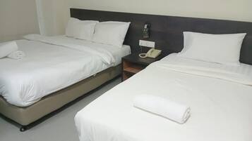 A hotel room with two single beds, each with white linens and pillows, a bedside table with a telephone, and a wall-mounted light fixture.
