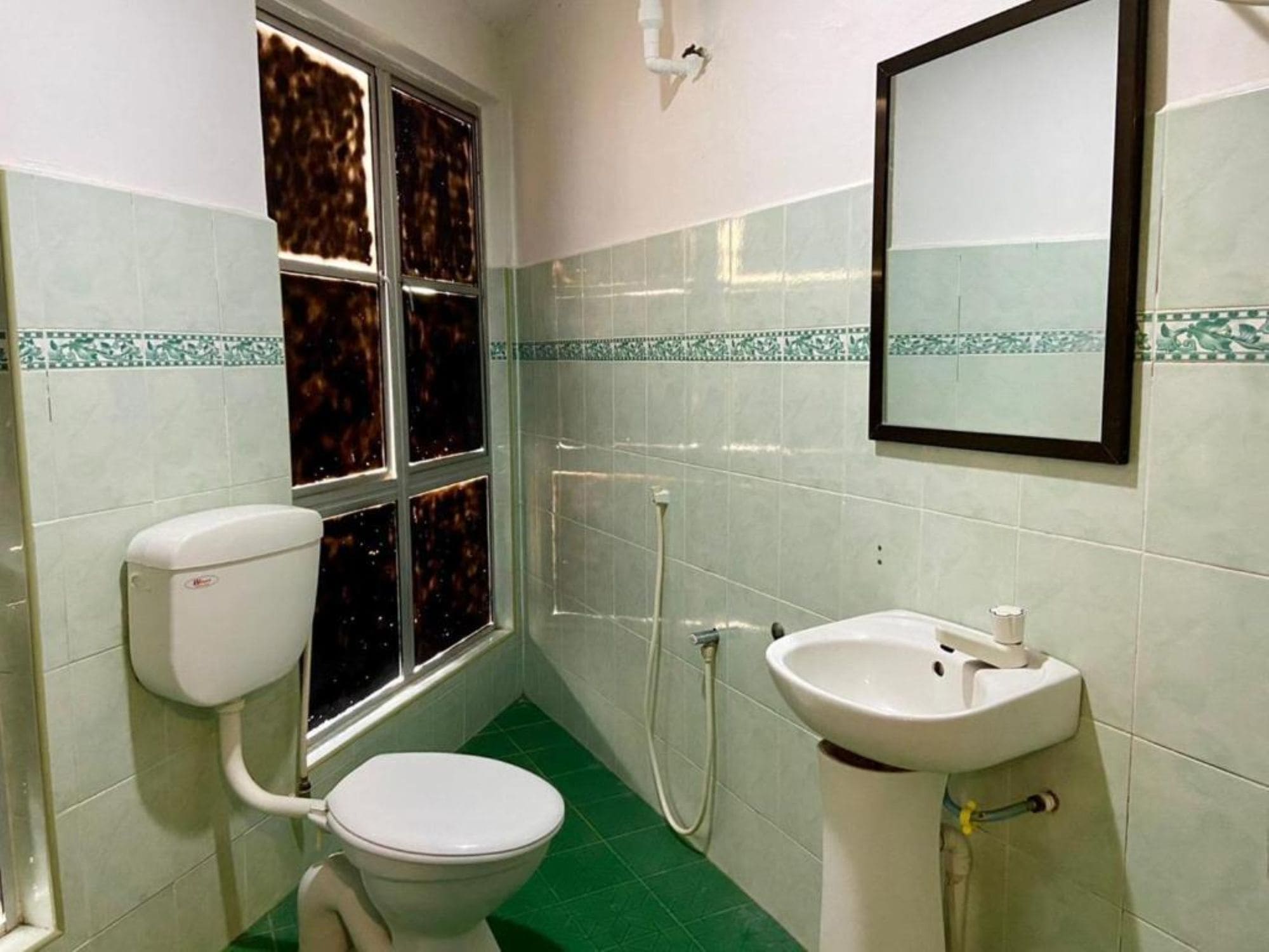 A bathroom with a toilet, sink, and window.