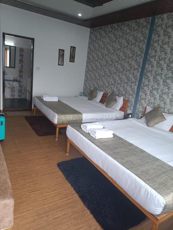 A hotel room with two single beds, a wooden floor, a dark rug, and a bathroom visible through an open door.