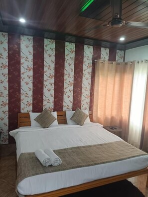 A hotel room with a large bed, wooden headboard, and a ceiling fan.