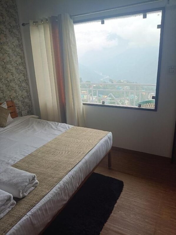 A bedroom with a bed, a window, and a view of a cityscape.
