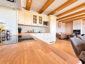 A modern kitchen with wooden beams, white cabinetry, and a central island. - Geilo ski-in/ski-out, apartment with great views (Hol)