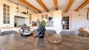 A modern kitchen with wooden beams, a dining table with a vase of flowers, and a wooden board game.