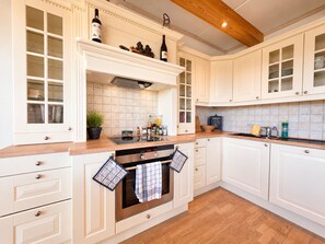 A kitchen with white cabinetry, a built-in oven, and a wooden countertop.