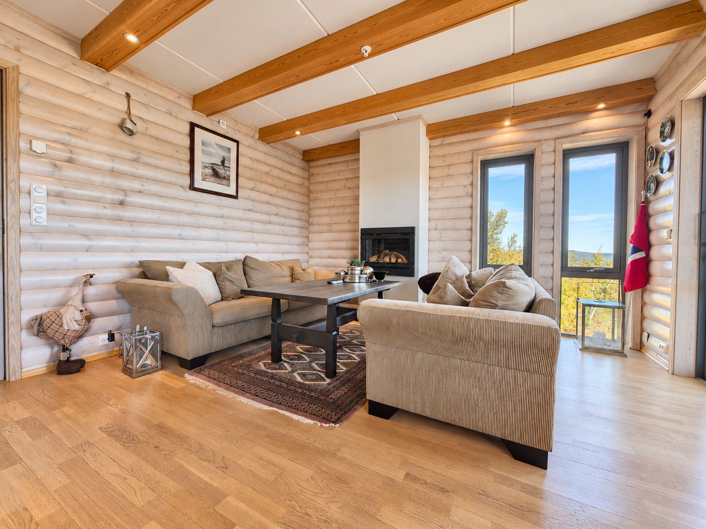 A log cabin interior with a fireplace, two sofas, a coffee table, and a rug.
