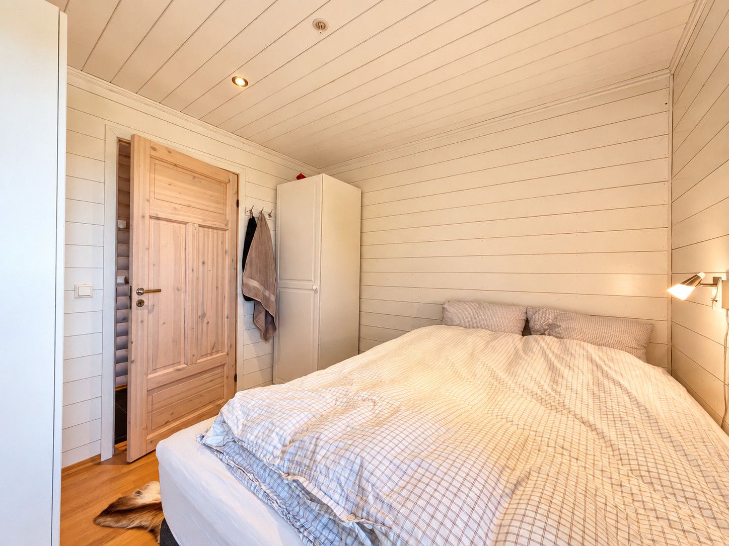 A bedroom with a bed, a wardrobe, and a door leading to a closet.
