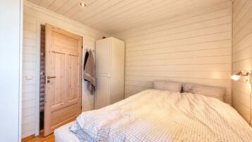 A bedroom with a bed, a wardrobe, and a door leading to a closet.