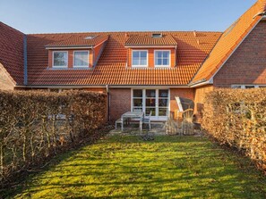 A two-story house with a red-tiled roof, a visible attic window, and a front door with glass panels. - House Section 30 "sea Lavender" (St. Peter-Ording)