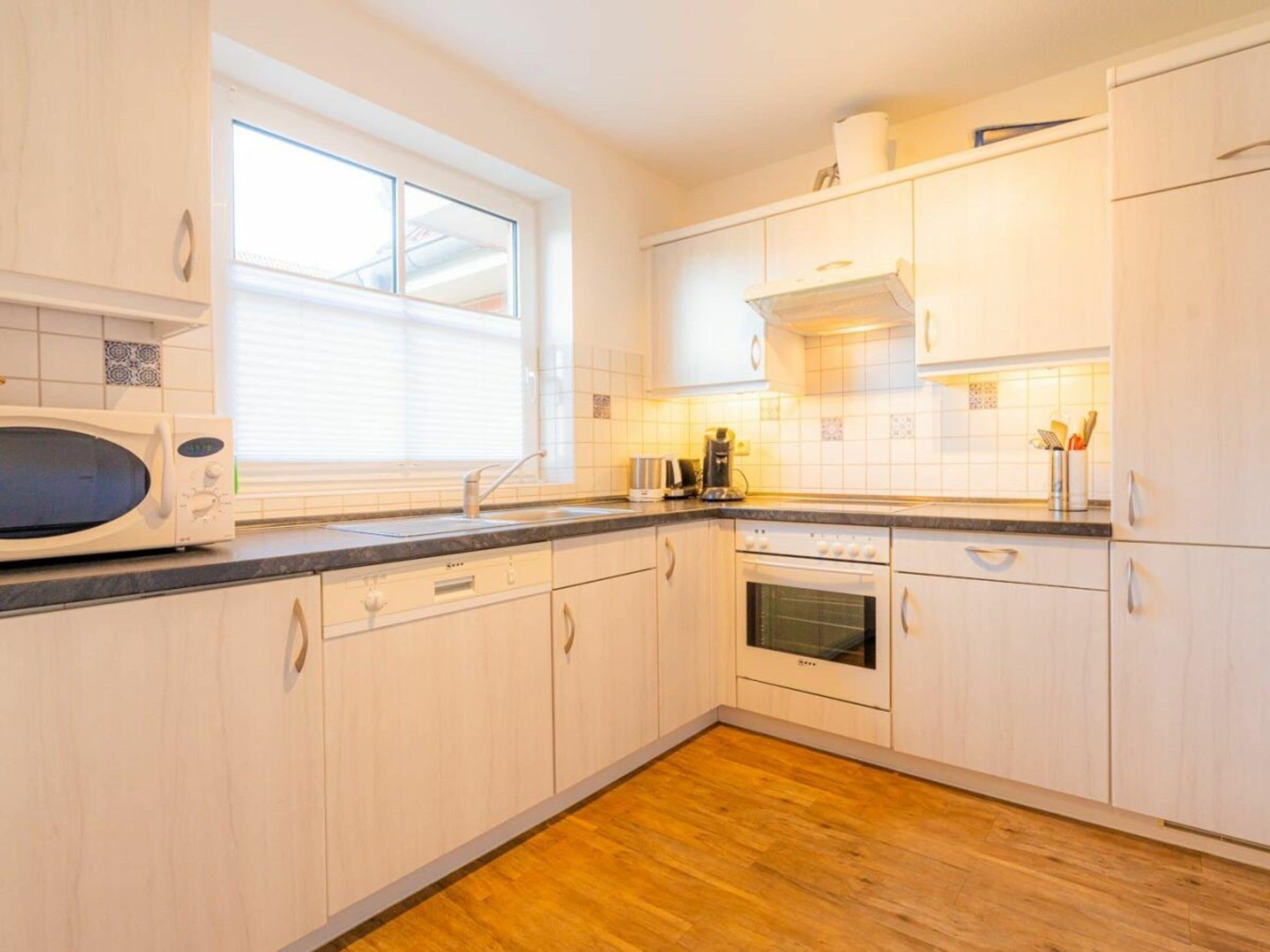 A kitchen with white cabinets, a microwave, a sink, and an oven.
