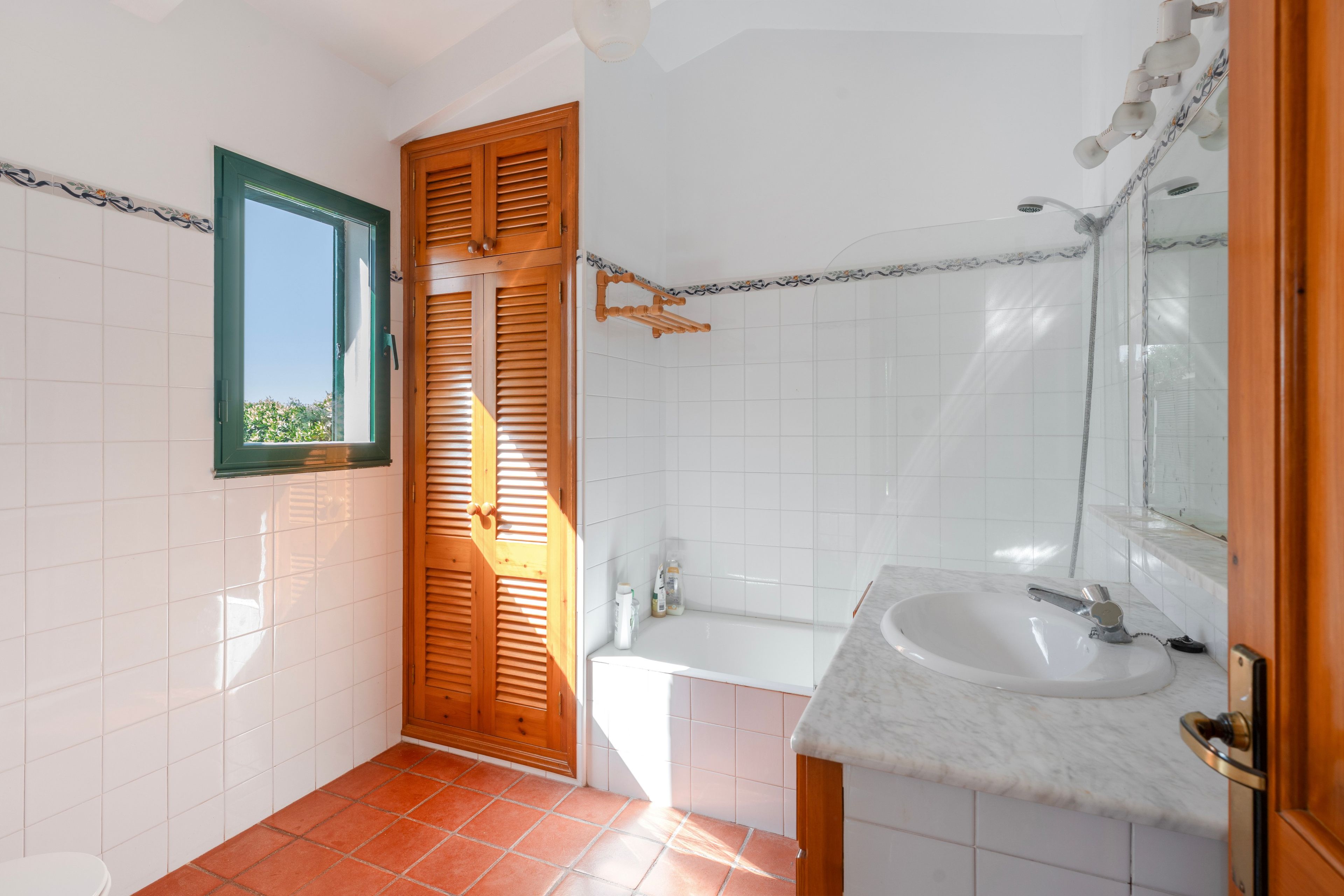 A bathroom with a white sink, a mirror, a shower, and a door with a window.