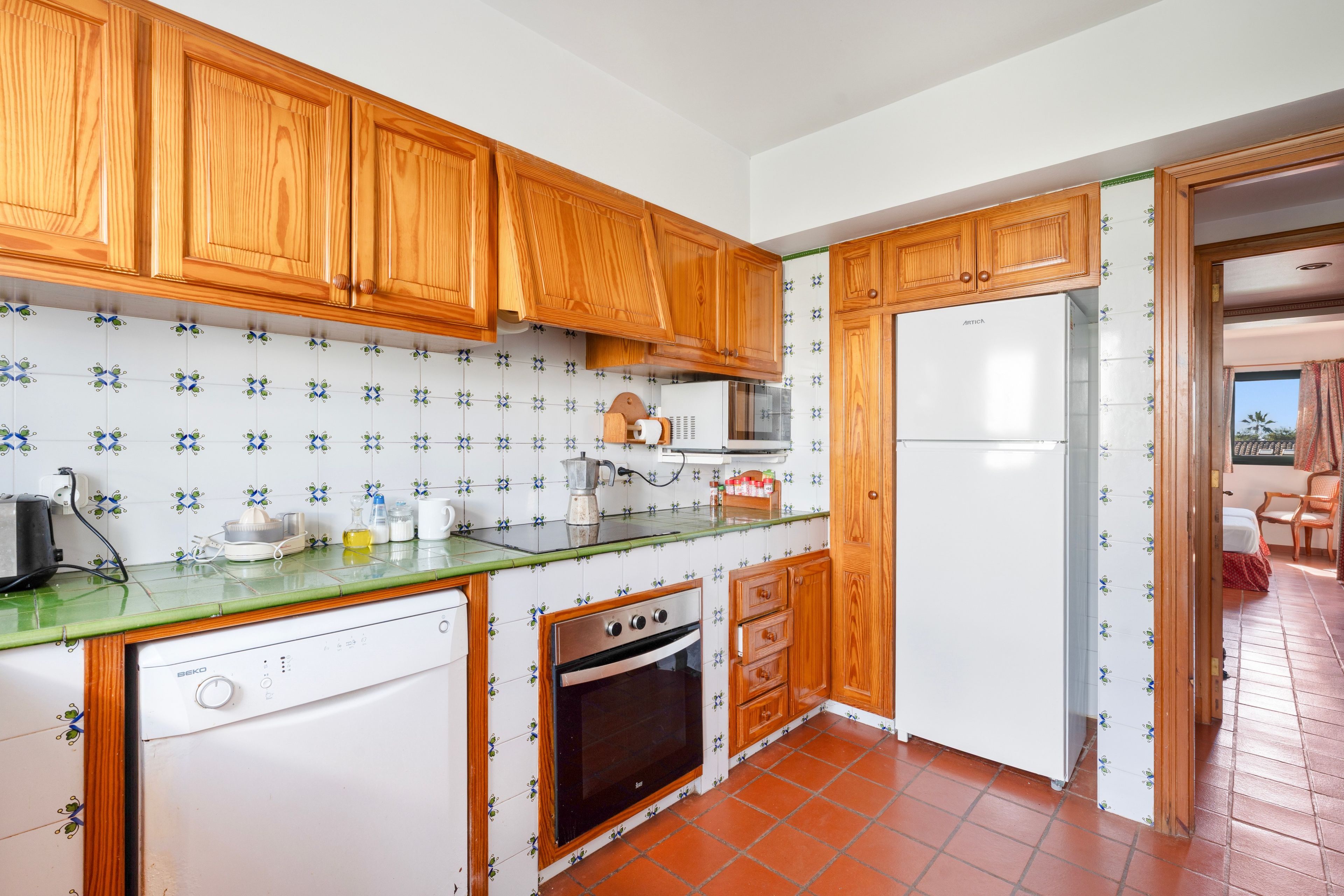 A kitchen with wooden cabinets, a dishwasher, a stove, and a refrigerator.