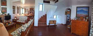 Ein geräumiges Wohnzimmer mit einer Couch, einem Fernseher und einer Treppe, die in ein weiteres Stockwerk führt.