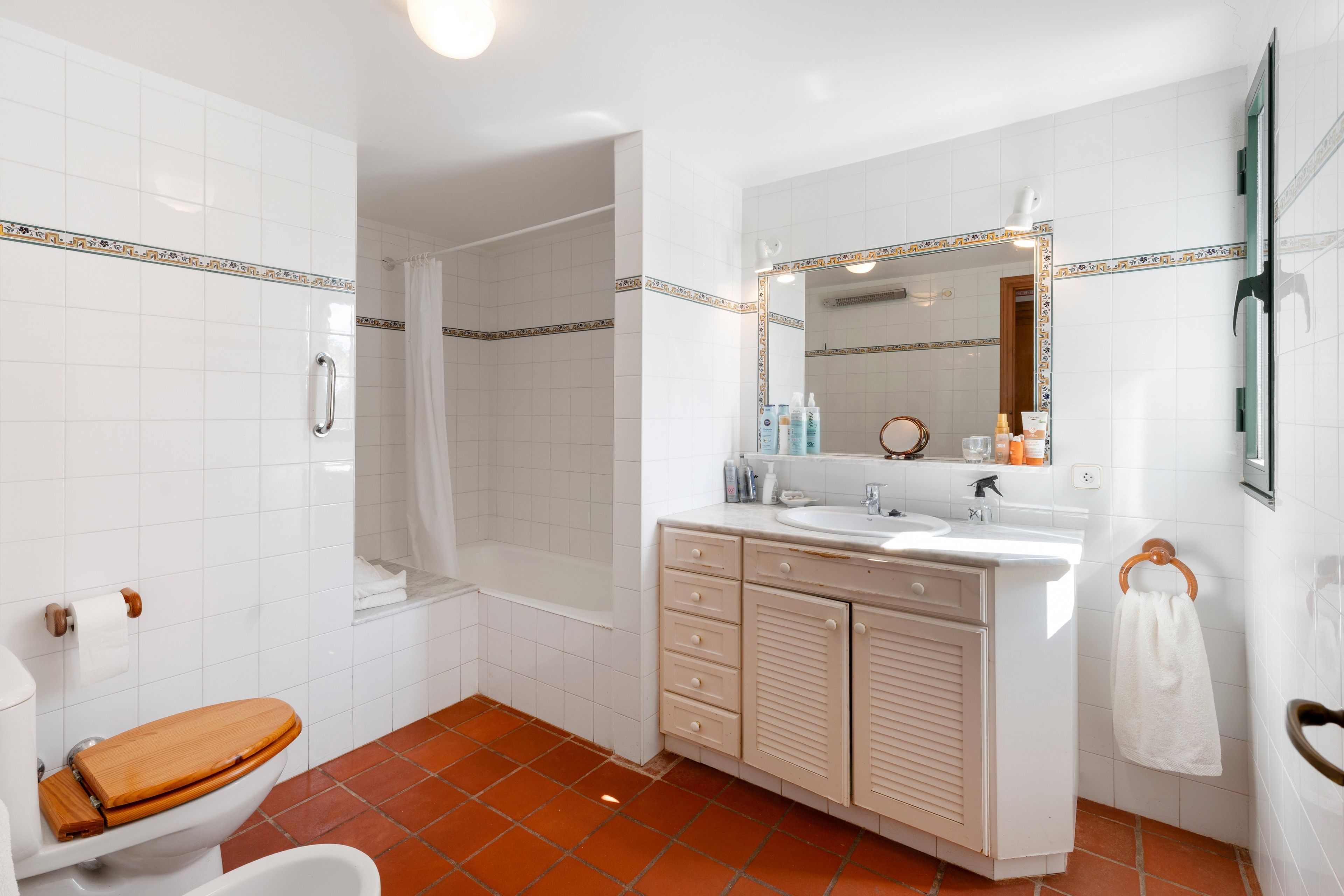 Une salle de bain équipée d’une douche, de toilettes, d’un meuble-lavabo avec un miroir et d’un porte-serviettes.
