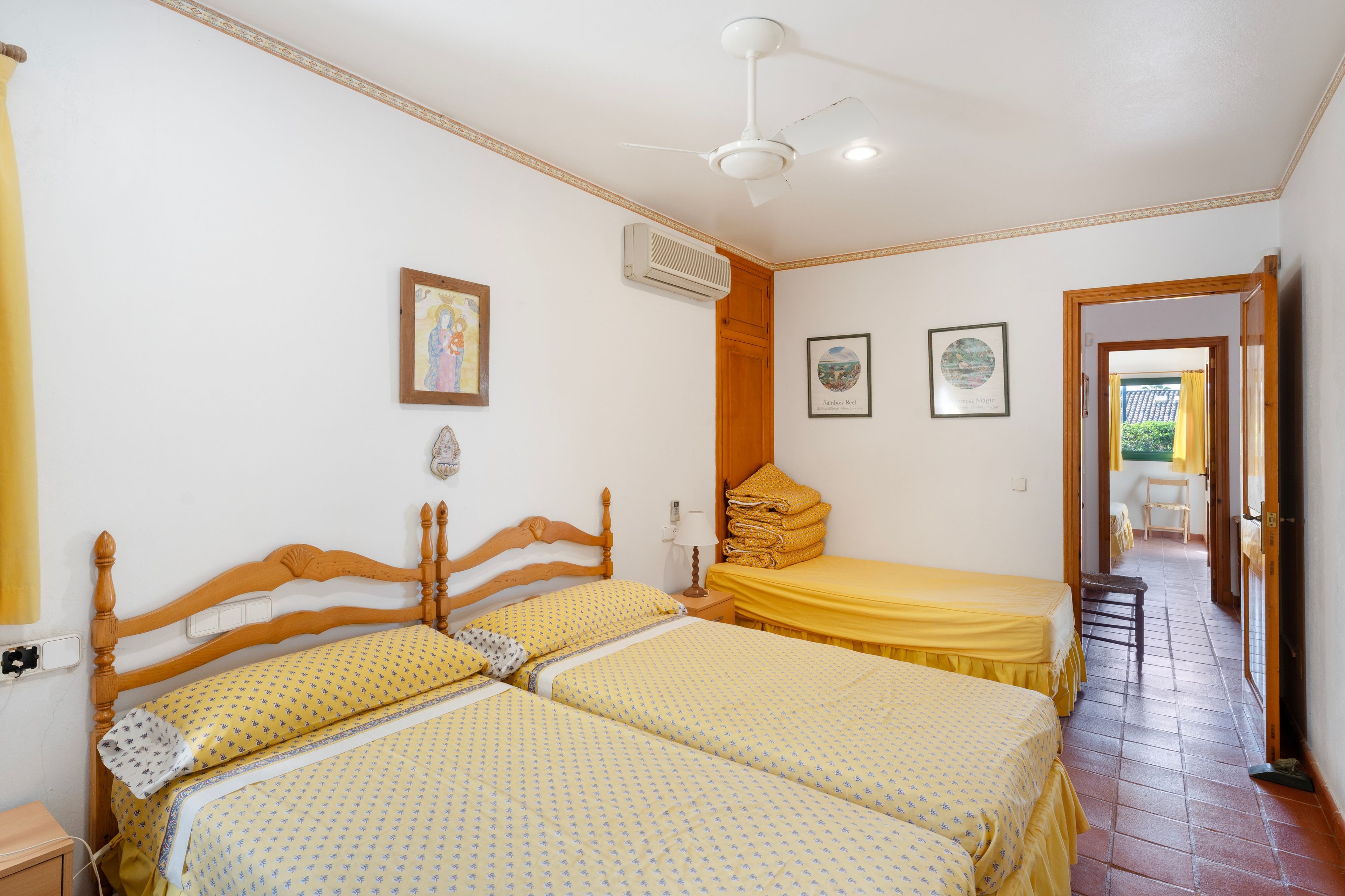 Habitación de hotel con dos camas, ventilador de techo y vistas al exterior.