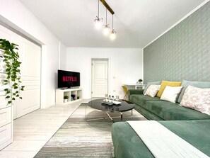 A modern living room with a green sofa, a coffee table, a flat-screen TV, and a plant. - The Bright IN Unirii Square next to the Old Town (București)