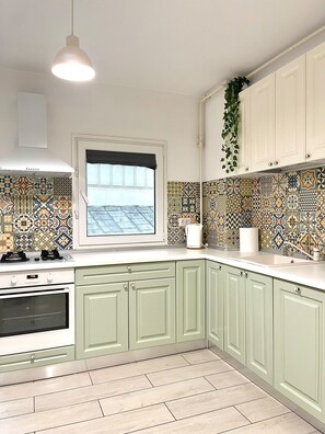 A kitchen with a window, patterned tiles, a hanging plant, and a stove. - The Bright IN Unirii Square next to the Old Town (București)