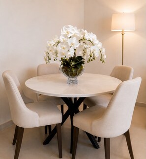 A round dining table with a glass bowl centerpiece, surrounded by four chairs with a dark base. - Address Beach Resort Residences Stunning High-Floor Views Private Beach Access (دبي)