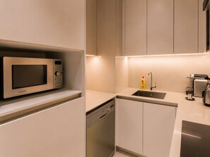 Een moderne keuken met een inbouwmagnetron, vaatwasser en koffieapparaat.