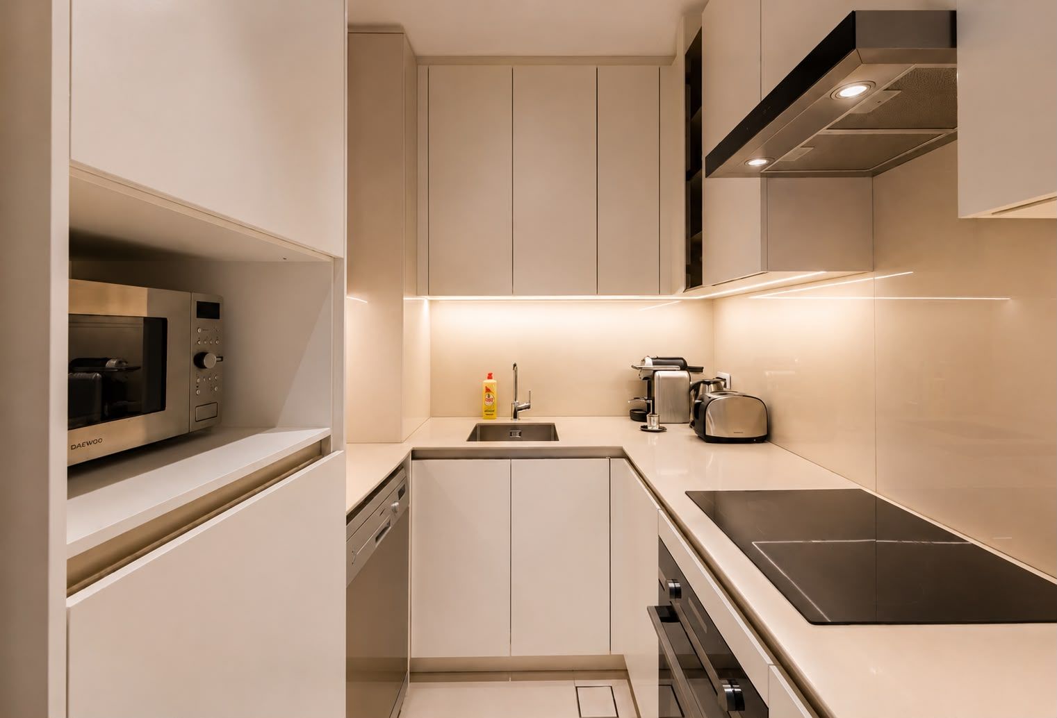 Una cocina moderna con microondas integrado, cafetera y tostadora.