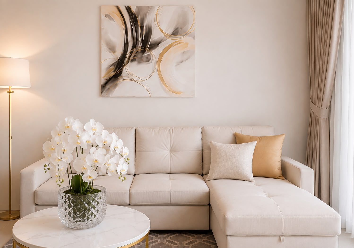 Una sala moderna con un sofá seccional color beige, una mesa de centro de cristal y orquídeas blancas.