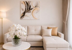 Ein modernes Wohnzimmer mit einem beigefarbenen Ecksofa, einem Glastisch und weißen Orchideen.