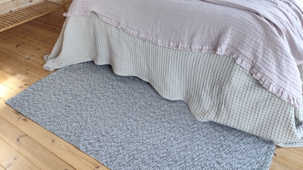 A bedroom with a wooden slat ceiling, a bed with multiple pillows, a wall-mounted shelf with clothes, and a small round table. - Peaceful 1-bedroom bed & breakfast in charming Chantraine (Chantraine)