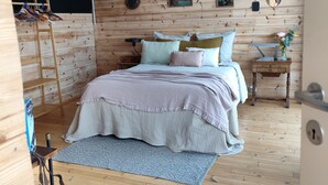 A wooden room with a bed, a hanging light fixture, a ladder, and wall-mounted pictures. - Peaceful 1-bedroom bed & breakfast in charming Chantraine (Chantraine)