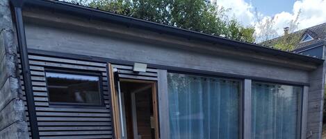 Un bâtiment moderne doté d’une piscine, d’une terrasse en bois et de grandes portes vitrées.