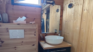A wooden cabin bathroom with a white sink, a mirror, and a wooden cabinet. - Peaceful 1-bedroom bed & breakfast in charming Chantraine (Chantraine)