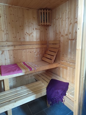 Un sauna en bois avec des bancs et un banc muni d’une serviette.