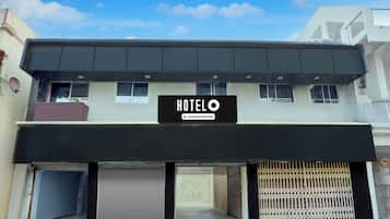 Un hotel con un letrero que indica que ofrece servicios para empresas. Presenta persianas cerradas en la planta baja y un tejado plano.