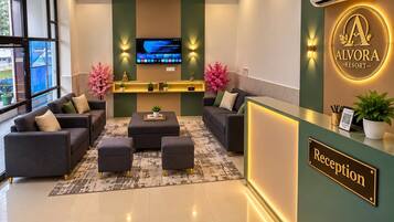 A reception area with a reception desk, sofas, a coffee table, and a TV screen.