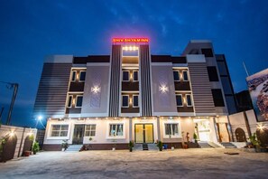 A hotel with a modern facade, a prominent entrance, and a sign reading 'SHIV SHYAMINN'.