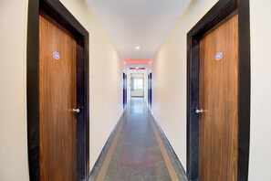 Un pasillo con dos puertas a cada lado, que conduce a una habitación con un ventanal al final.