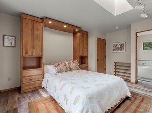 Ein Schlafzimmer mit einem Bett, einem Holzschrank und einem Oberlicht.