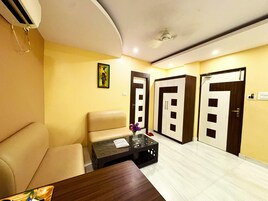 Habitación de hotel con sofá, una mesita, un jarrón decorativo y una puerta con espejo.