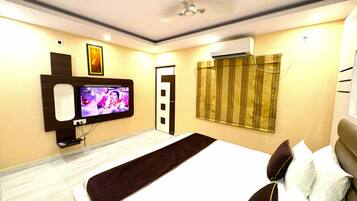 Habitación de hotel con cama, televisor montado en la pared, aire acondicionado y una puerta con cortina.
