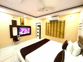 Habitación de hotel con cama, televisor montado en la pared, aire acondicionado y una puerta con cortina.