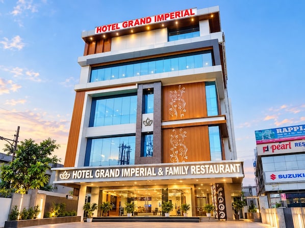 Um hotel com vários andares e uma placa grande com a inscrição 'HOTEL GRAND IMPERIAL & FAMILY RESTAURANT'.