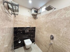 Un baño con inodoro, toallero, cabezal de ducha y aire acondicionado de pared.