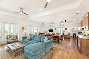 A spacious living area with a large sofa, dining table, and ceiling fans. - It's 5 O'Clock Somewhere! Ocean Views, Steps to the Beach by Tybee Cottages (Tybee Island)