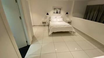 Een slaapkamer met een bed, twee nachtkastjes en een bedbank.