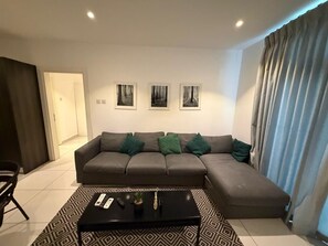 Una sala de estar moderna con un sofá seccional, una mesa de centro y tres cuadros en la pared.