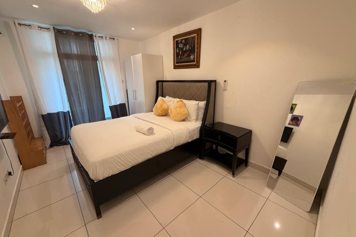 Un dormitorio con cama, mesitas de noche, un armario y un espejo.
