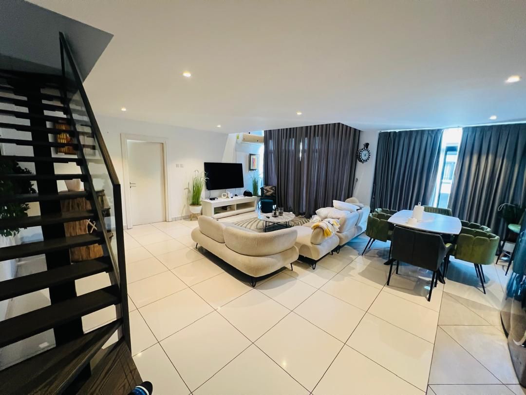 Ein modernes Wohnzimmer mit einer Couch, einem Esstisch und einer Treppe.