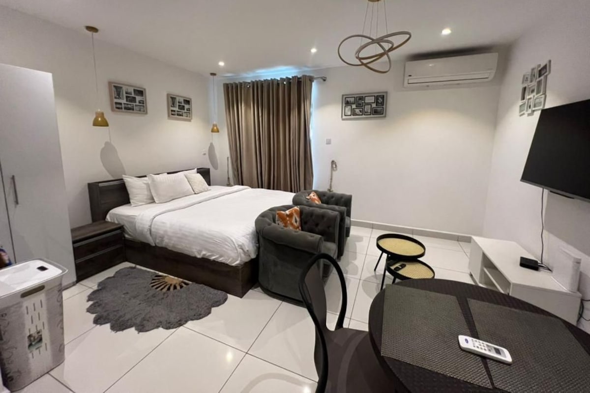 Un dormitorio moderno con una cama, un sofá, una mesita y un televisor.