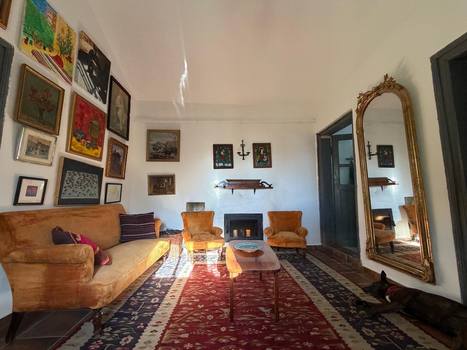 Una sala de estar con chimenea, un espejo grande y varias obras de arte enmarcadas en las paredes.
