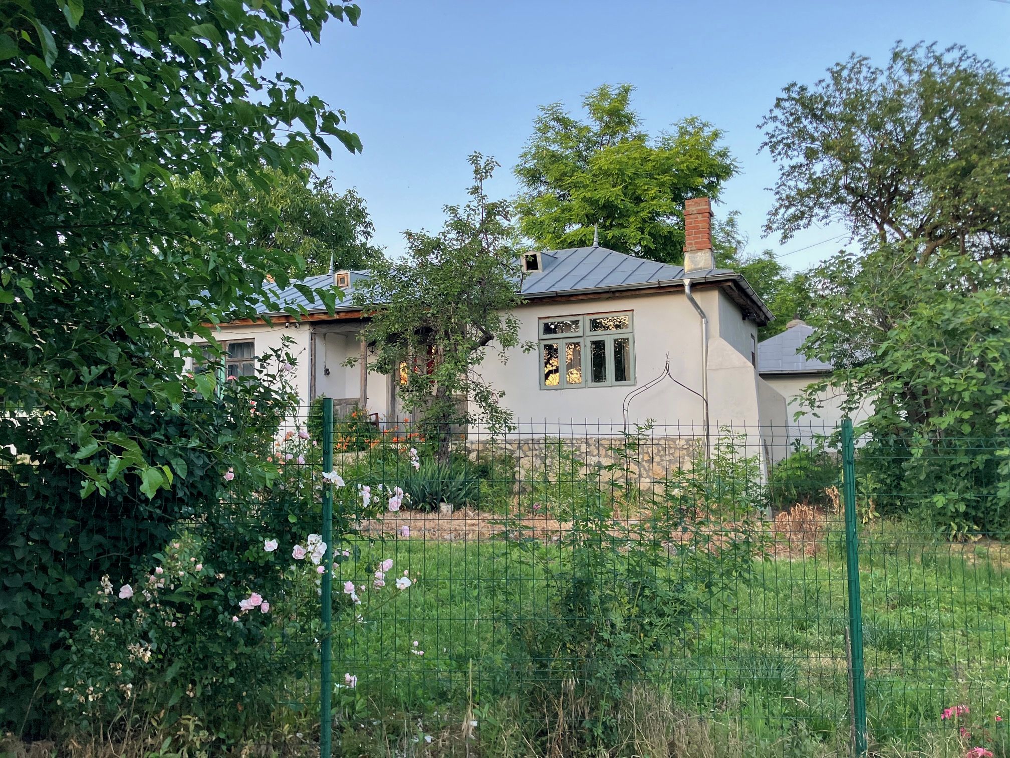 Una casa con jardín cercado, rodeada de vegetación.