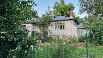 Una casa con jardín cercado, rodeada de vegetación.